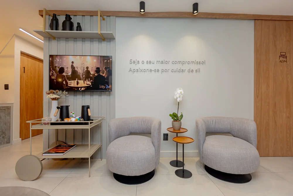 Lounge de espera da clínica com o slogan da marca na parede